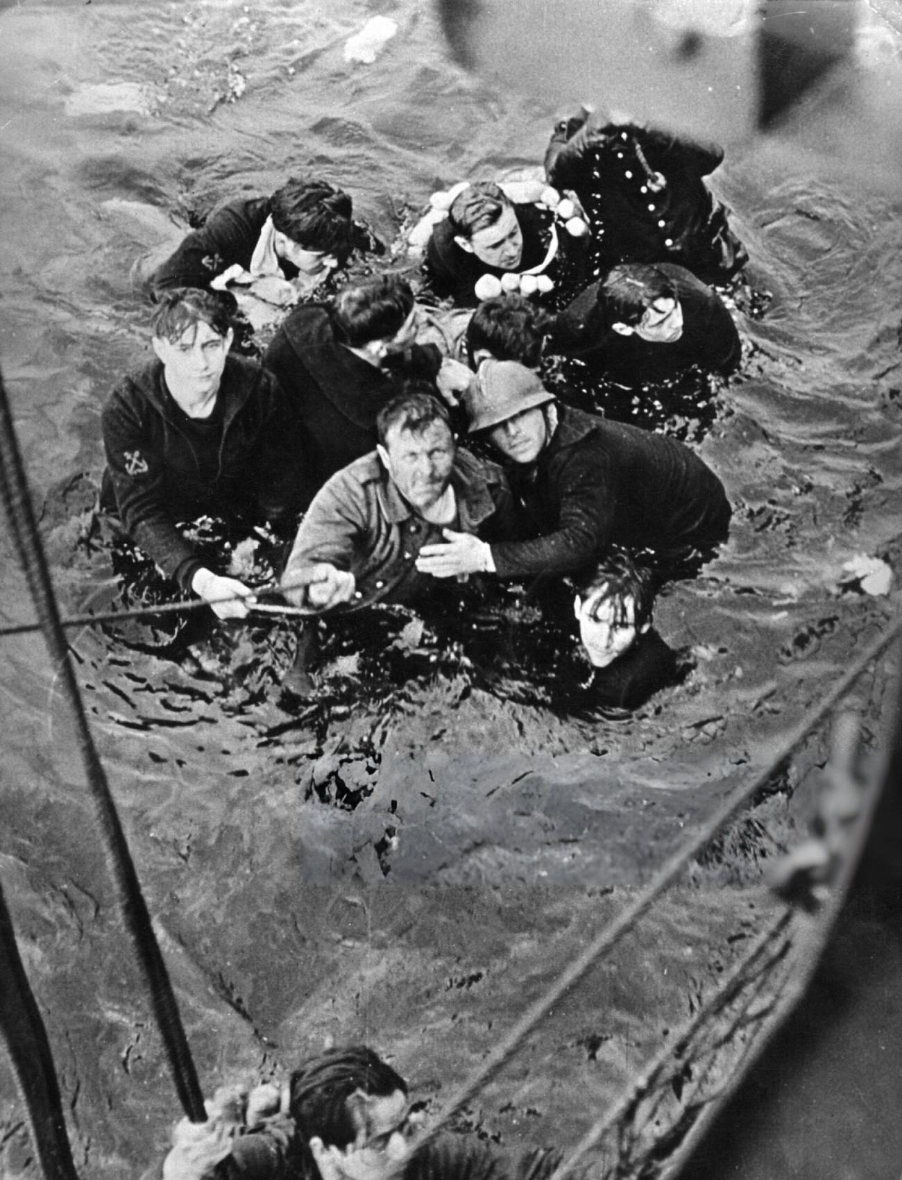 #30 Crew members of the French destroyer Bourrasque, sunk by mine off Nieuwpoort during the Dunkirk evacuation, are hauled aboard a British vessel from their sinking life-raft, 1940.