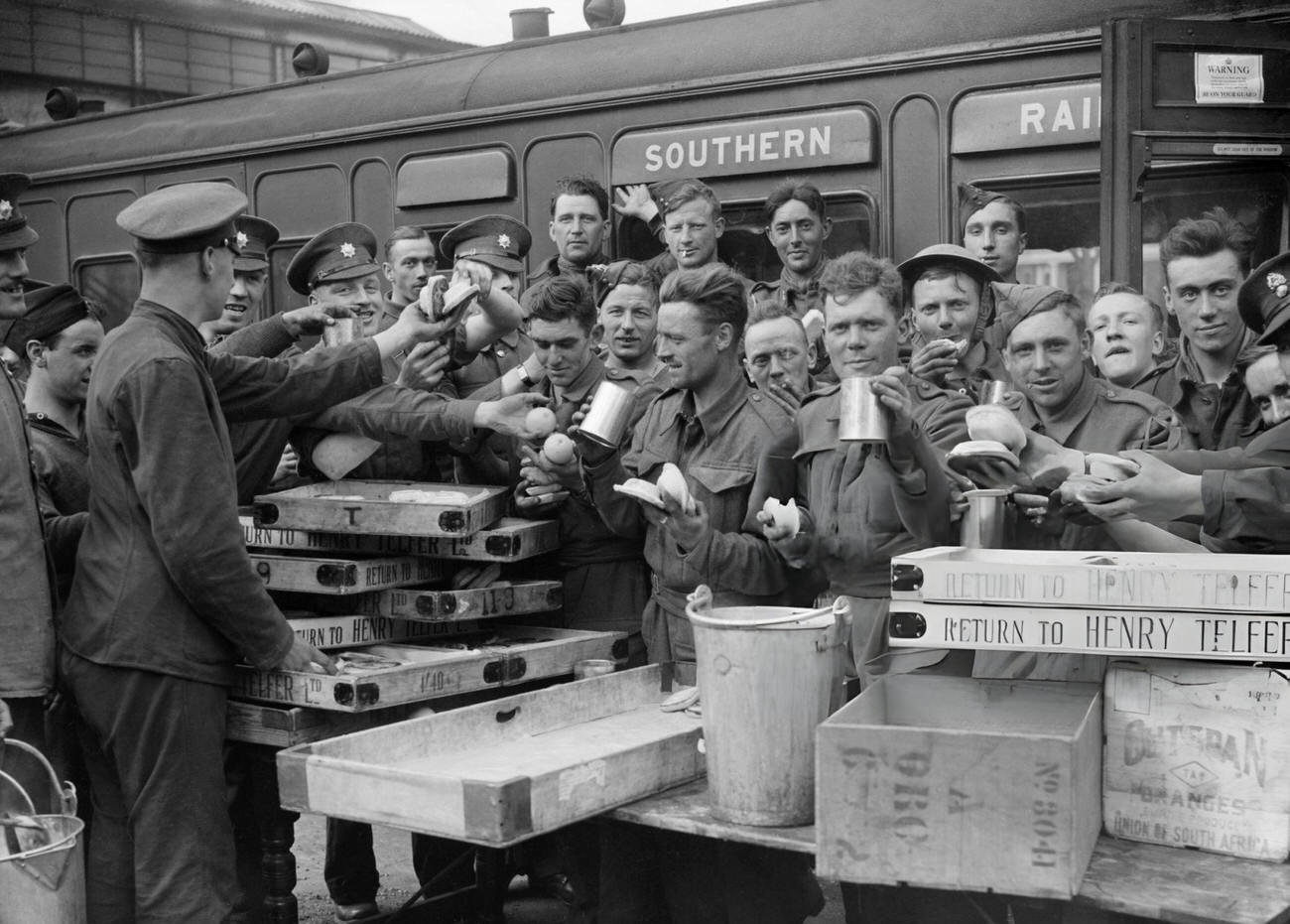 #34 Evacuated troops enjoying tea and other refreshments at Addison Road station, London, 1940.