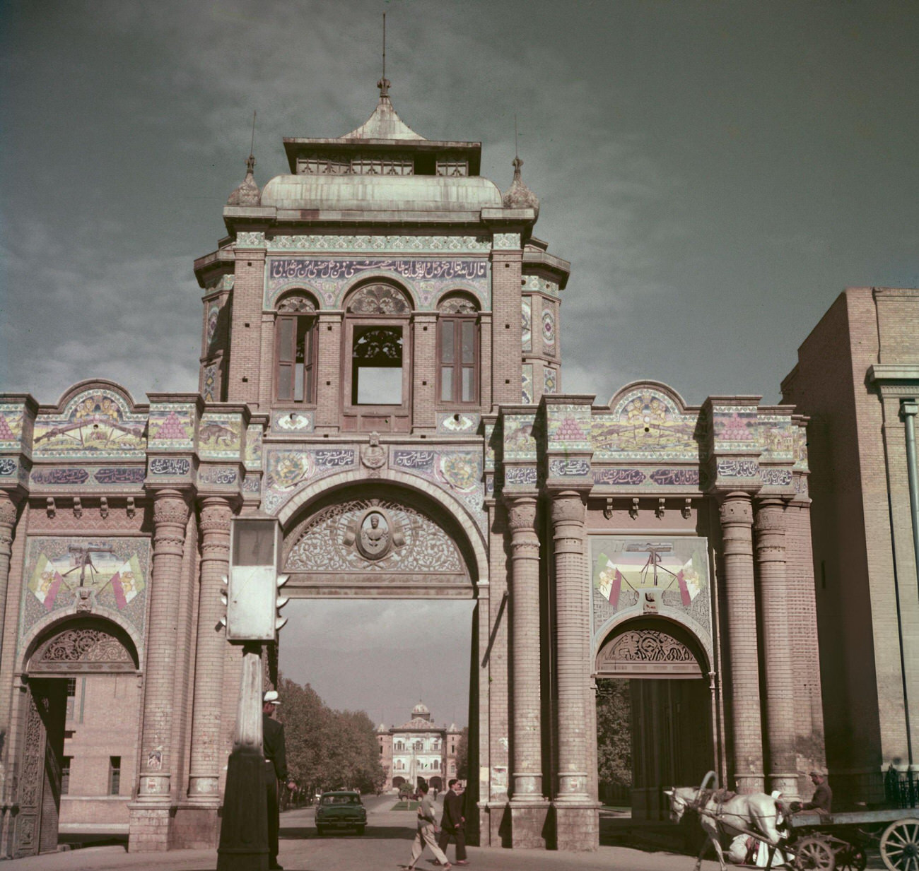 #23 Pedestrians pass a decorative archway over a road leading to the Ministry of Defence building in Tehran, 1960s.