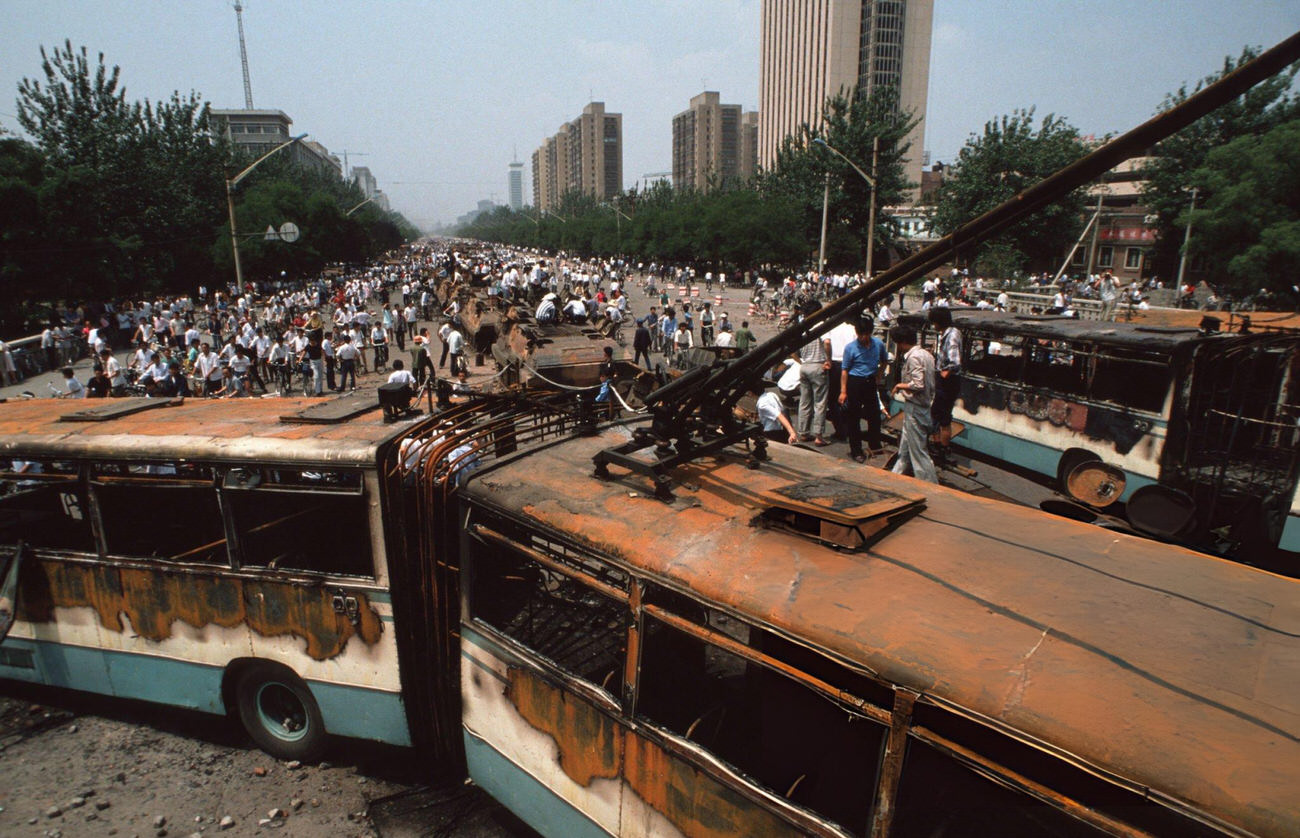 #41 Onlookers look at buses and Chinese Army trucks and vehicles that were damaged or destroyed, 1989.