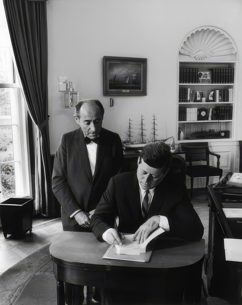 #7 President John F. Kennedy signs Alfred Eisenstaedt’s autograph book after a portrait session in the oval office, 1962.