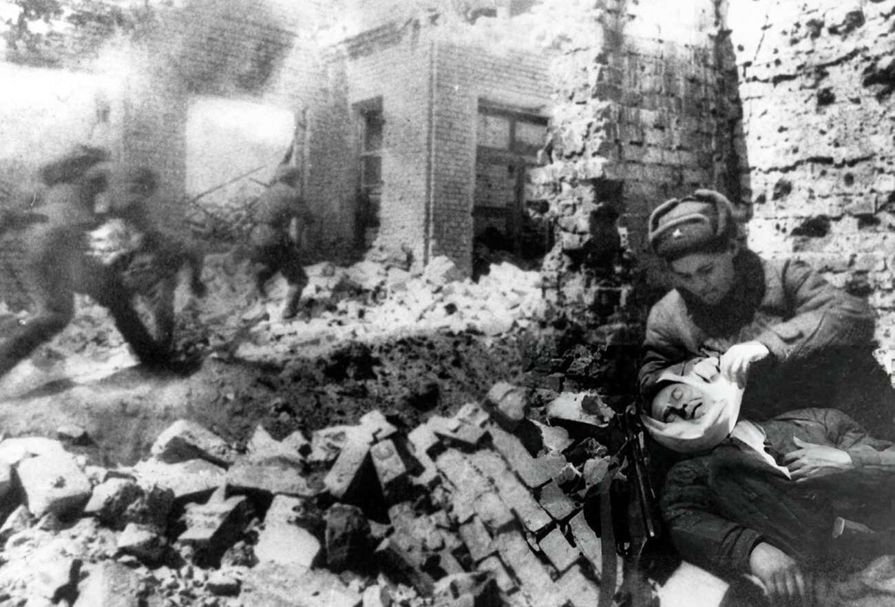#40 Nurse bandaging a wounded soldier during street fighting in Stalingrad, 1942.