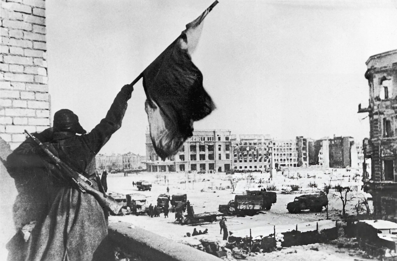 #1 A Russian soldier waves a flag while standing on a balcony during the Battle of Stalingrad, 1942.