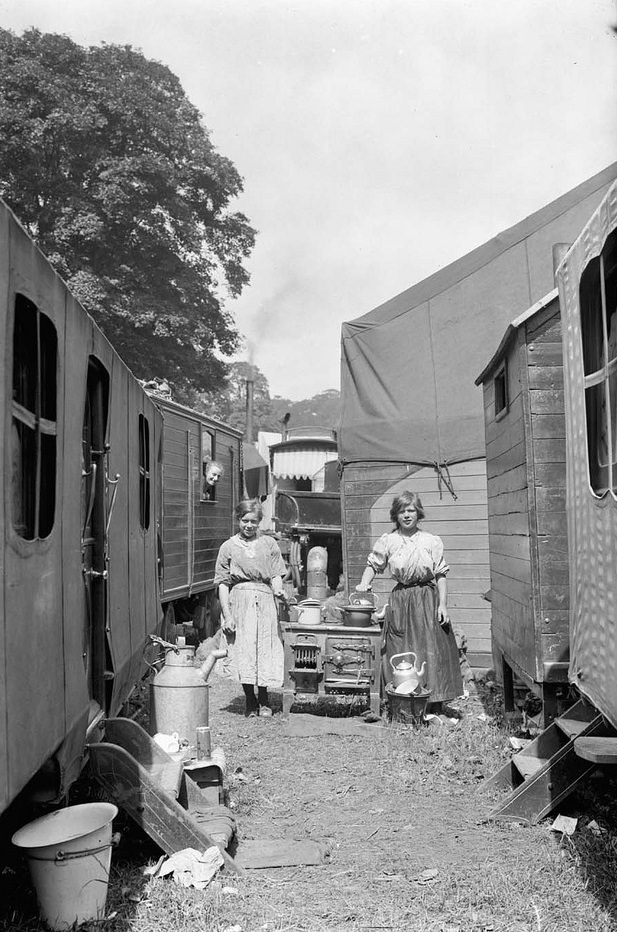 #8 Outdoor stove. Two girls stood next to an old stove in amongst a group of caravans.