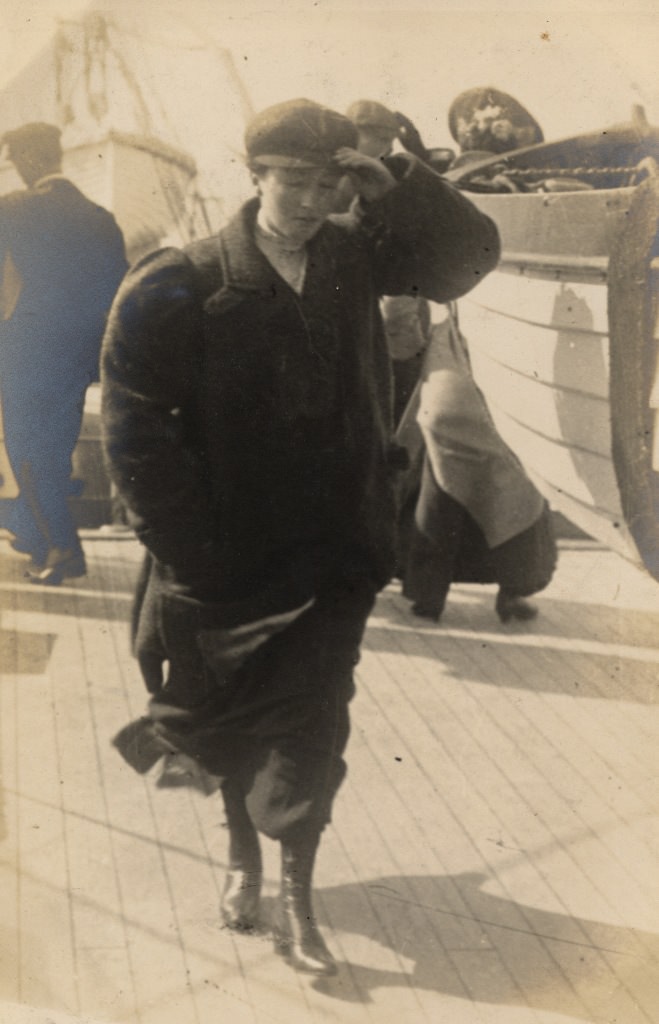 #14 The woman of the couple on the ferry, wearing a masculine-looking coat and hat.