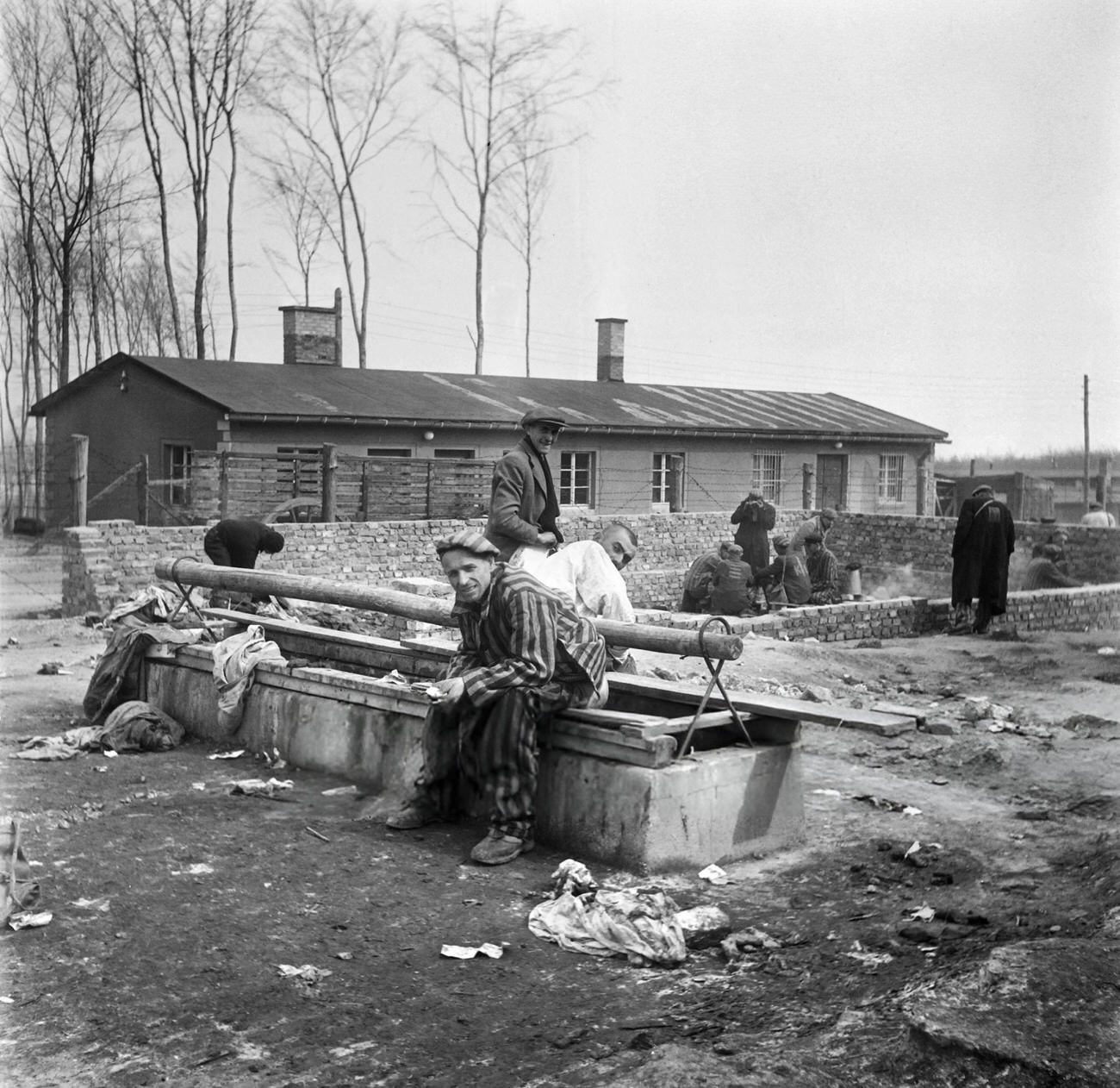 #35 Survivors of the Buchenwald Nazi concentration camp sit on a latrine, 1945.
