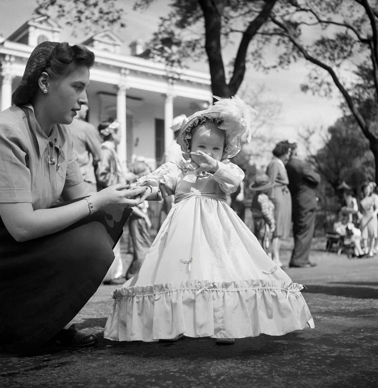 #48 A Mother Guides Her Little Girl as She Toddles in Her Elaborate Mardi Gras Gown and Bonnet, 1950s.