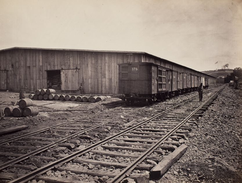 #20 Railroad cars and warehouses in a railroad yard, 1865