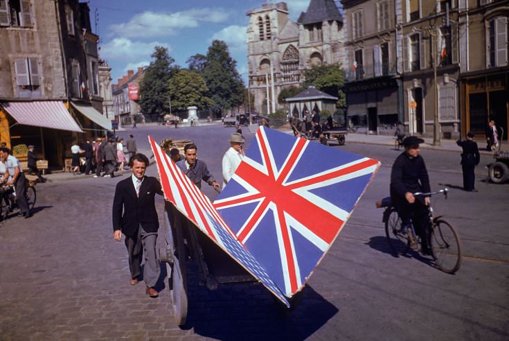 #20 Frenchmen transport painted British and American flags for use in a parade, summer 1944