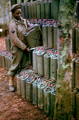 #4 An American corporal stacks cans of gasoline in preparation for the upcoming invasion of France, Stratford-upon-Avon, England, May 1944