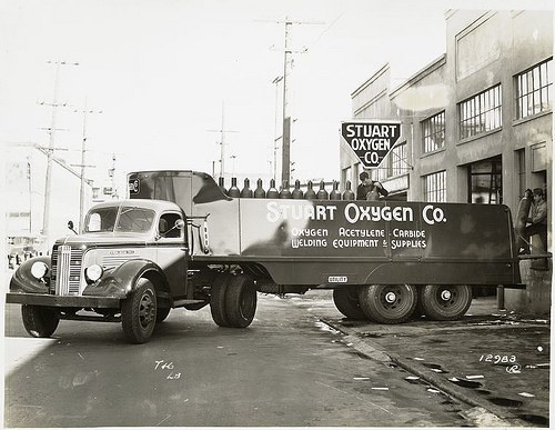 Model T 16 – L 8 in front of Stuart Oxygen Co. loading gas cylinders.