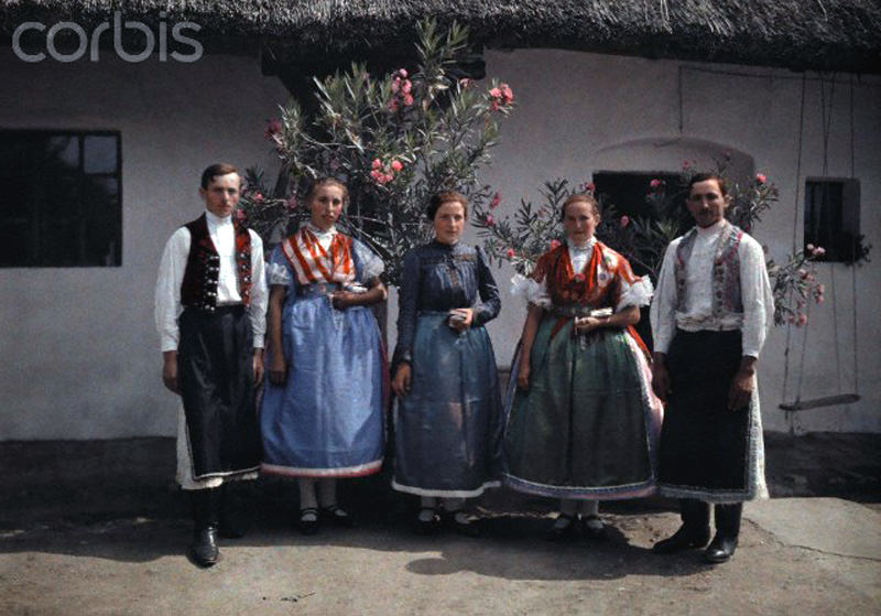 #10 Farmers and girls stand before a flower-decorated house in Sopron, Hungary, January 1930.