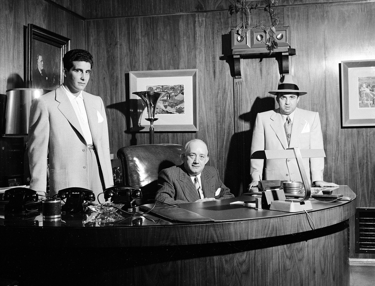#17 Mickey Cohen’s enforcer, “Johnny Stomp” Stompanato (famously stabbed and killed by Lana Turner’s 14-year-old daughter, Cheryl Crane, in 1958), business manager Mike Howard and Cohen pose in Cohen’s office in Los Angeles, 1949.