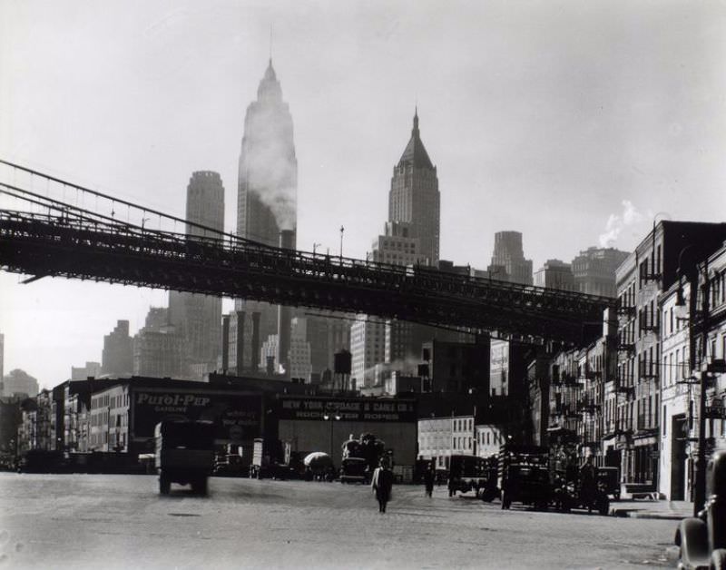 #16 Waterfront, South Street, Manhattan. rooklyn Bridge span as it reaches land above South Street near James, tall buildings rise beyond.