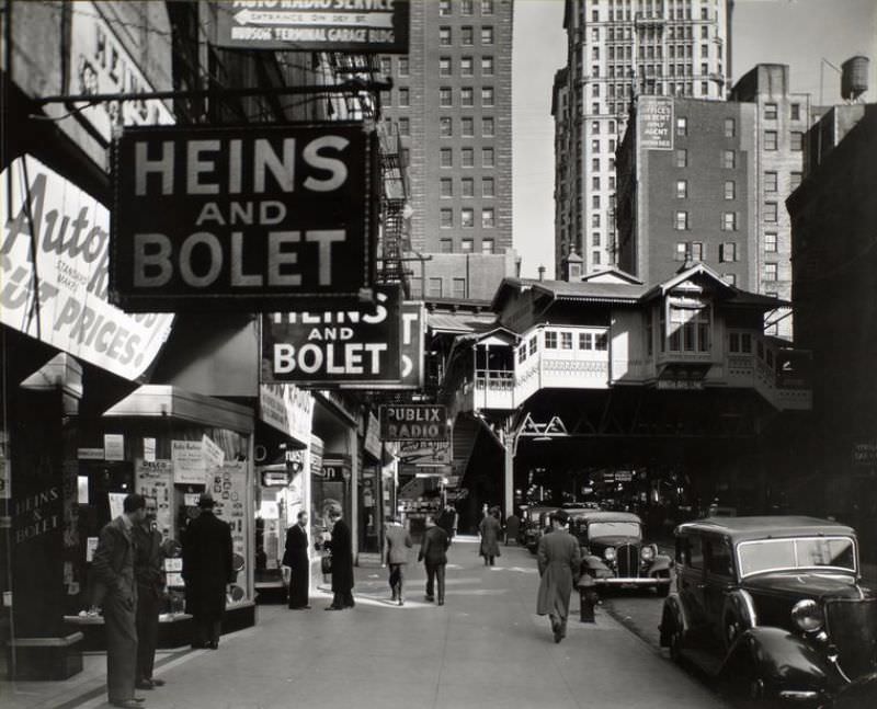 #46 Radio Row, Cortlandt Street, Manhattan. Men window shop in store selling radios, elevated railroad station, Ninth Avenue line, right center, subway entrance visible.