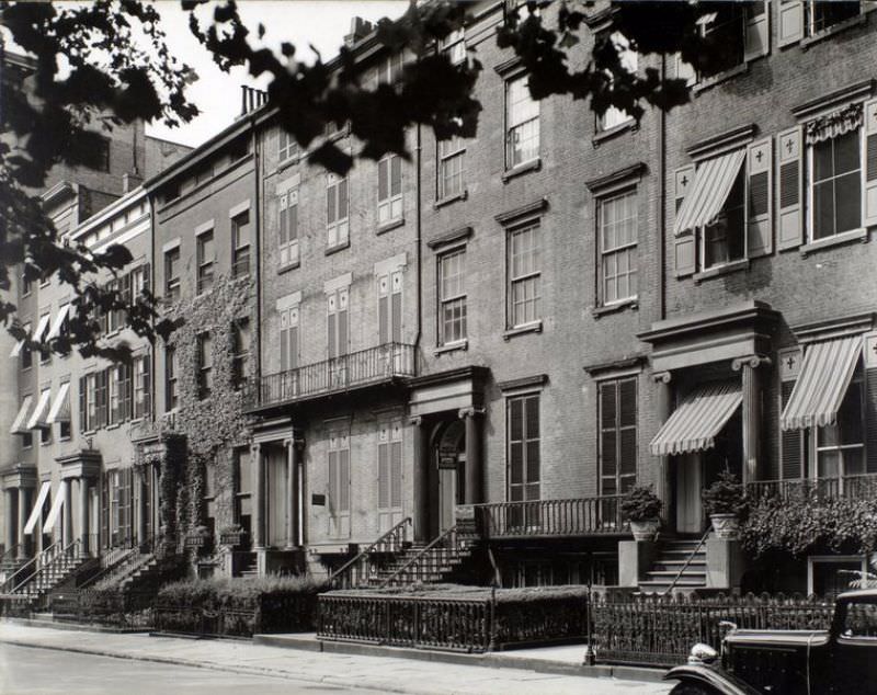 #63 Washington Square North, nos. 121-125, Manhattan. Row of brick houses, all with pairs of columns at door, ones at ends have awnings; house for rent is shuttered; Jaguar car partially visible.