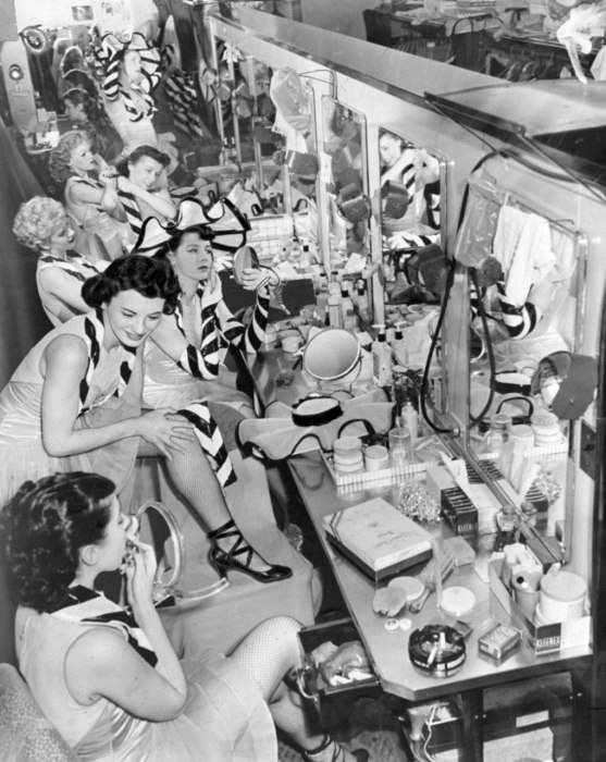 #66 Backstage at the vanity area in 1952, the Rockettes set their makeup with powder, adjust their stockings, and stick in their final bobby pins before going onstage.