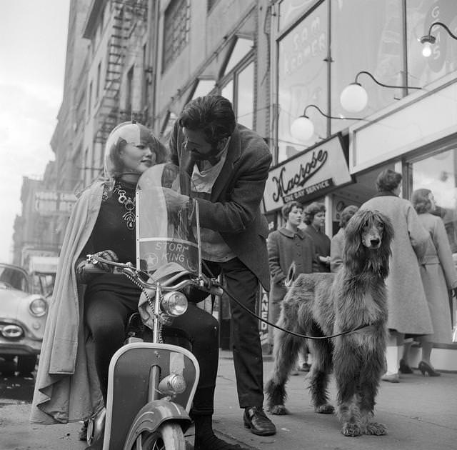 #2 American jeweller, Sam Kramer helping one of his ‘Space Girls’ with her motorbike helmet on a Greenwich Village street, 1955.