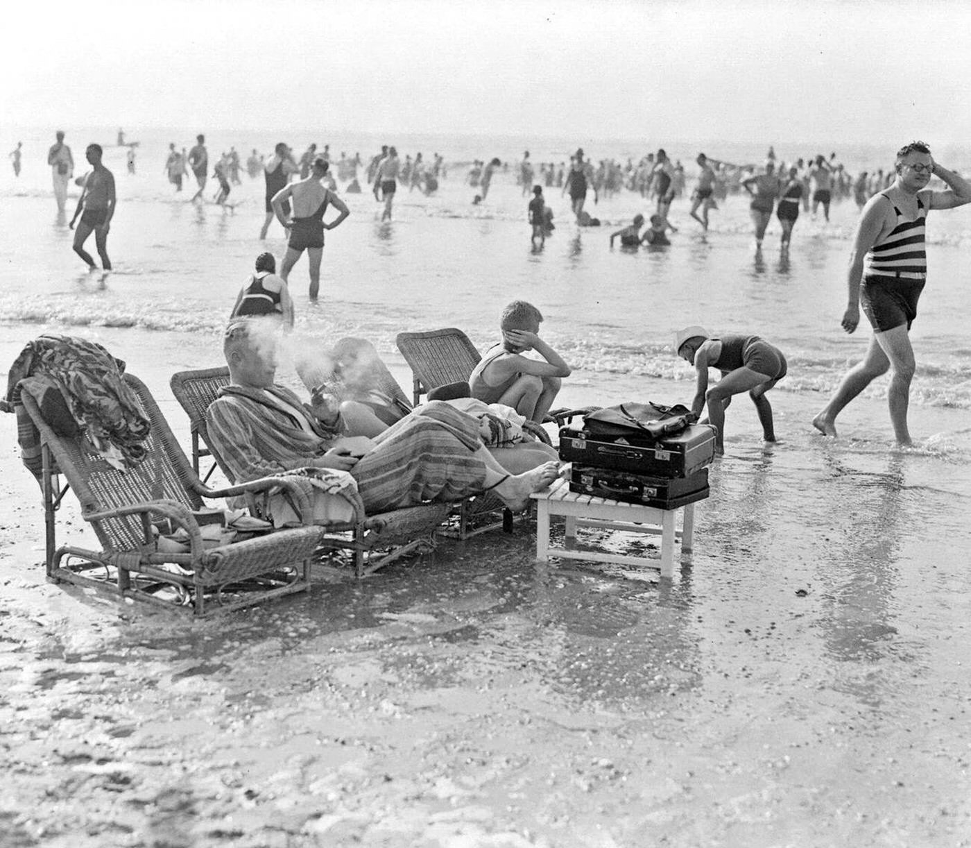 #18 Bathers sitting on wicker loungers in the sea at the beach, 1930s.