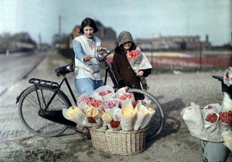 #4 Two young girls stand near flowers being sold on the side of the road in Haarlem, 1930s.