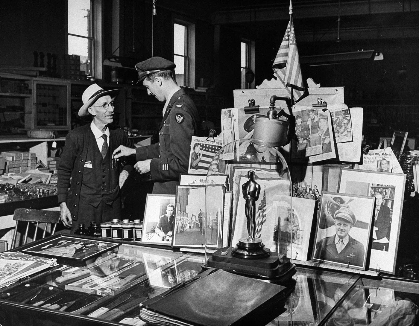 #13 Jimmy Stewart, back from WWII, talks with the oldest employee of his family’s hardware store in Pennsylvania, George Little; nearby is a table of various mementos, including Stewart’s Best Actor Oscar for The Philadelphia Story.