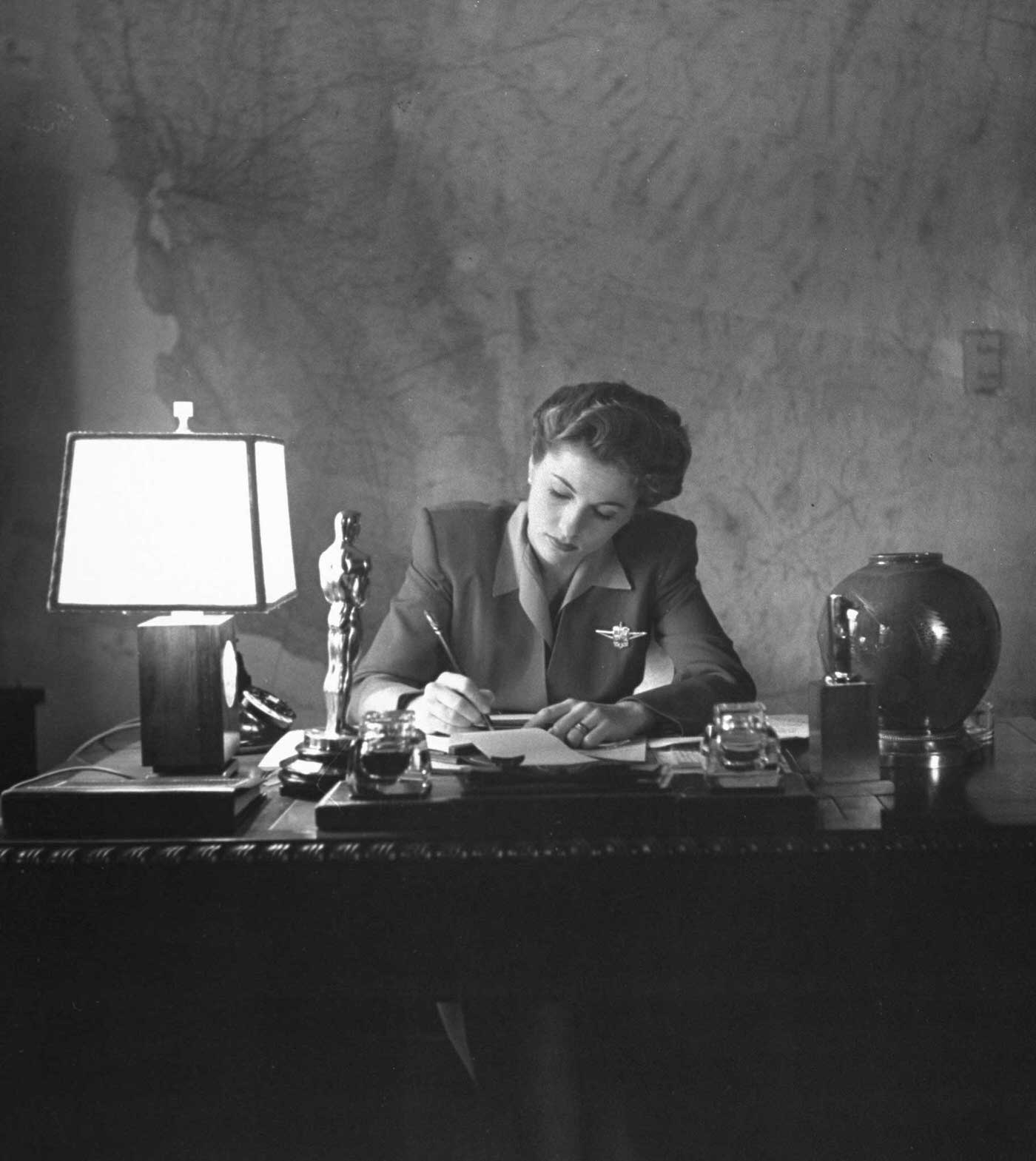 #3 Joan Fontaine doing the household bookkeeping next to the Oscar she won for her role in Hitchcok’s Suspicion, 1942.