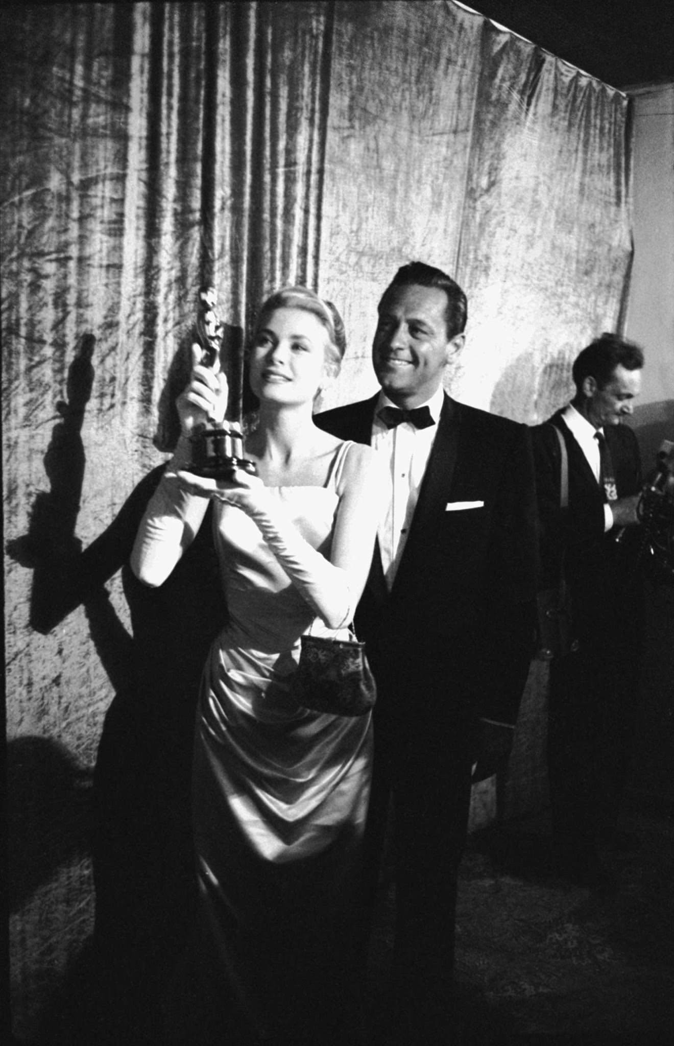 #5 Grace Kelly with the Oscar she won for her role in The Country Girl, 1955. William Holden, her co-star in the movie, stands behind her.