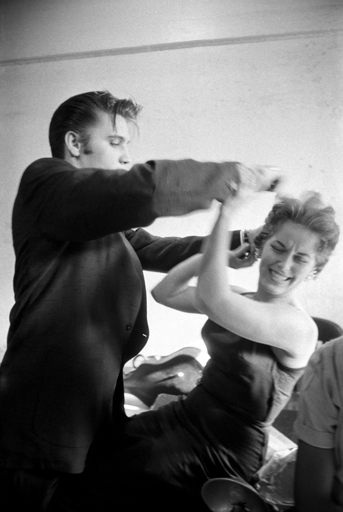 Backstage at the Mosque Theatre, Richmond, Virginia, Elvis messing with Bobbi Owen’s hair, 1956.