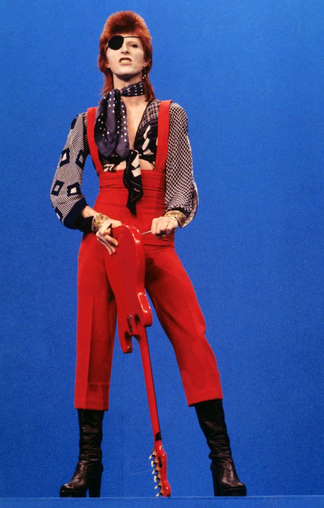 David Bowie in an eye patch and red overalls performing “Rebel Rebel” on TopPop in Hilversum, Netherlands, 1974.
