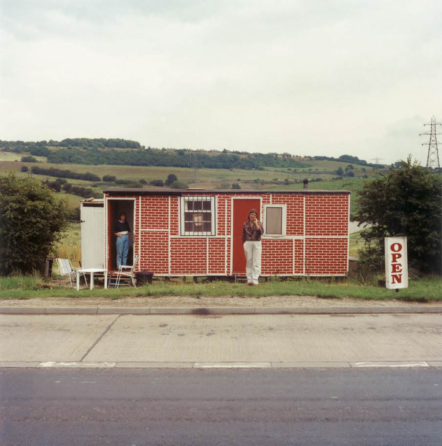 #11 Elaine Whitehead & Linda, Red Brick Cafe, Dewsbury Road, summer 1992. ‘Sandwiched between the tarmac and the sky, and with those red bricks, Elaine’s cafe is so Leeds.’