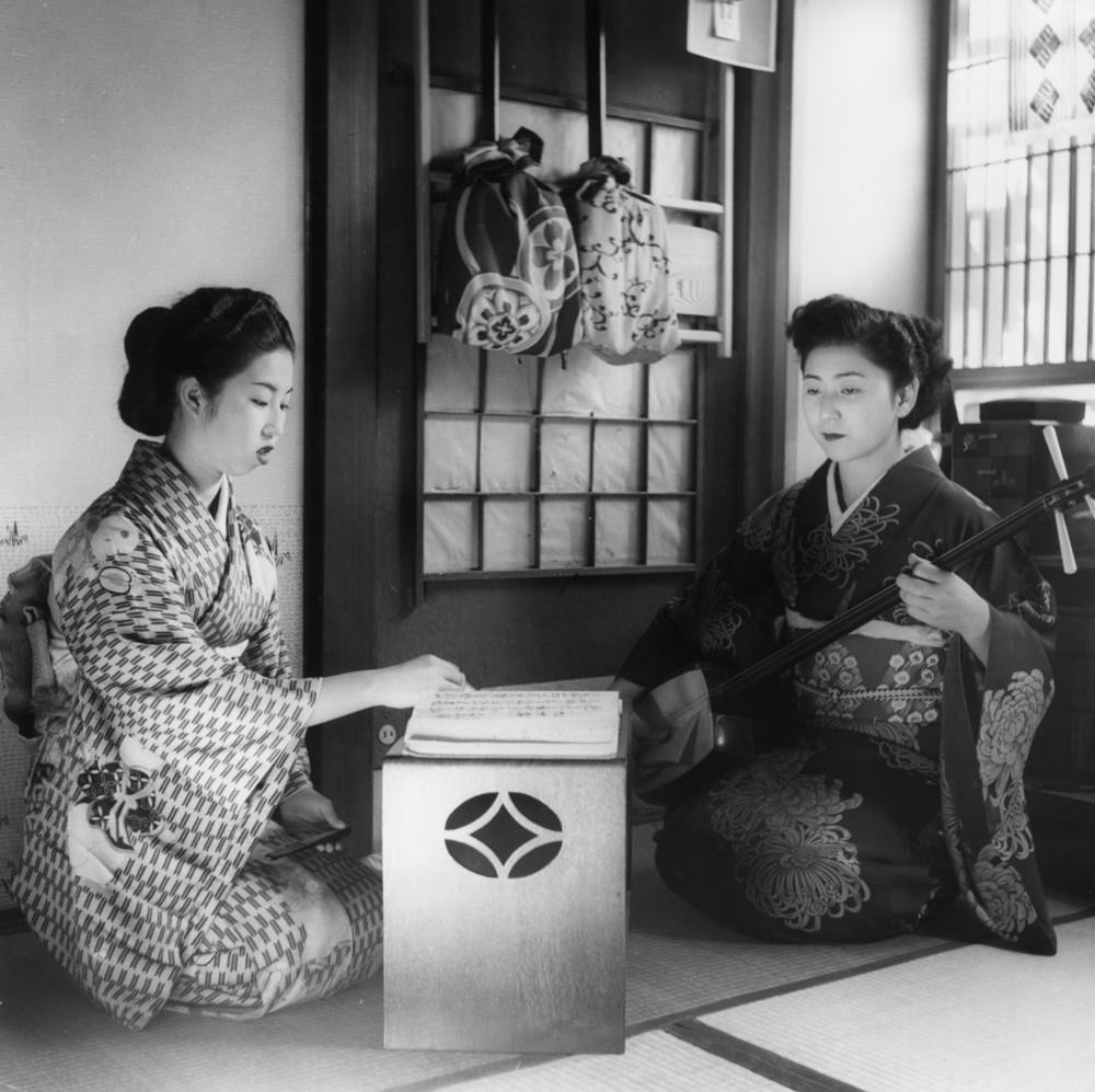 #1 Geisha girls practicing their art; one plays a samisen, 1950s.