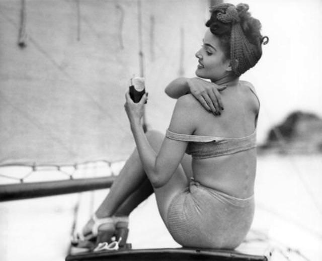 #9 Circa 1950s: Woman applying suntan lotion.