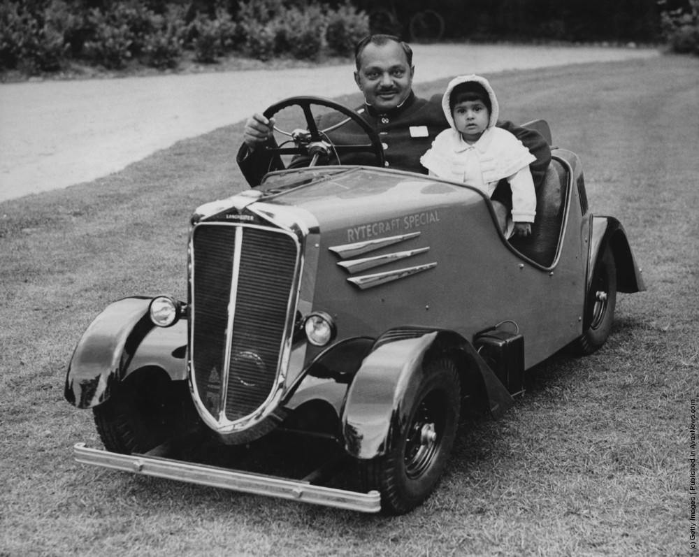 Sir K.S. Digvijaysinhji (1895–1966), the Maharajah of Nawanagar, with his daughter Princess Harshad Kunverba in a Rytecraft Special midget car on the Maharajah’s estate near Dorking, Surrey. The Maharajah has bought the car for his daughter for use on the estate when she is out with her nurse. 22nd June 1937.