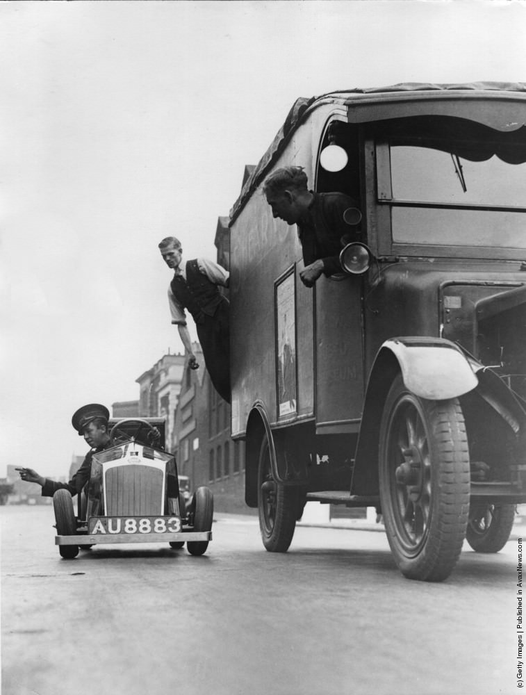 A tiny one-horsepower car being used by a florist for delivering blooms to customers attracts some attention on the London roads. 17th November 1934.