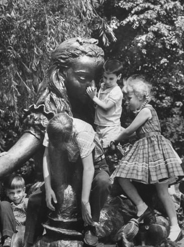 #16 In a wonderland for climbers a bronze Alice is cluttered with children who have scrambled over Mad Hatter and other Lewis Carroll creatures
