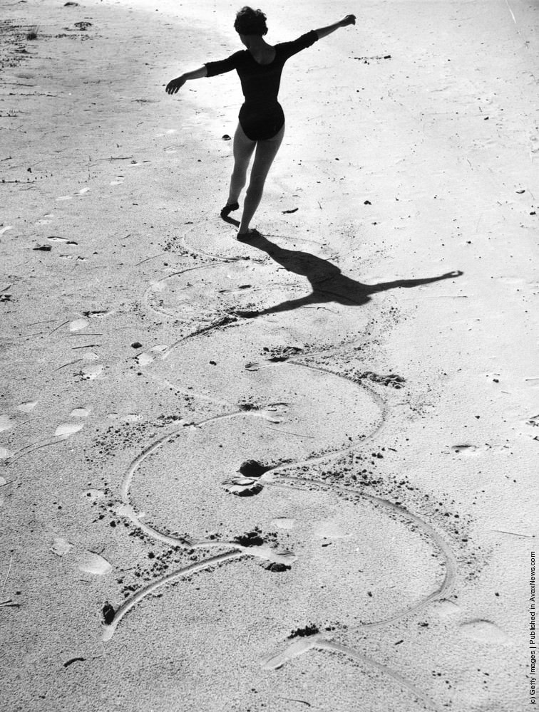 #14 A ballet dancer drawing circles in the sand with her toes, 1955.