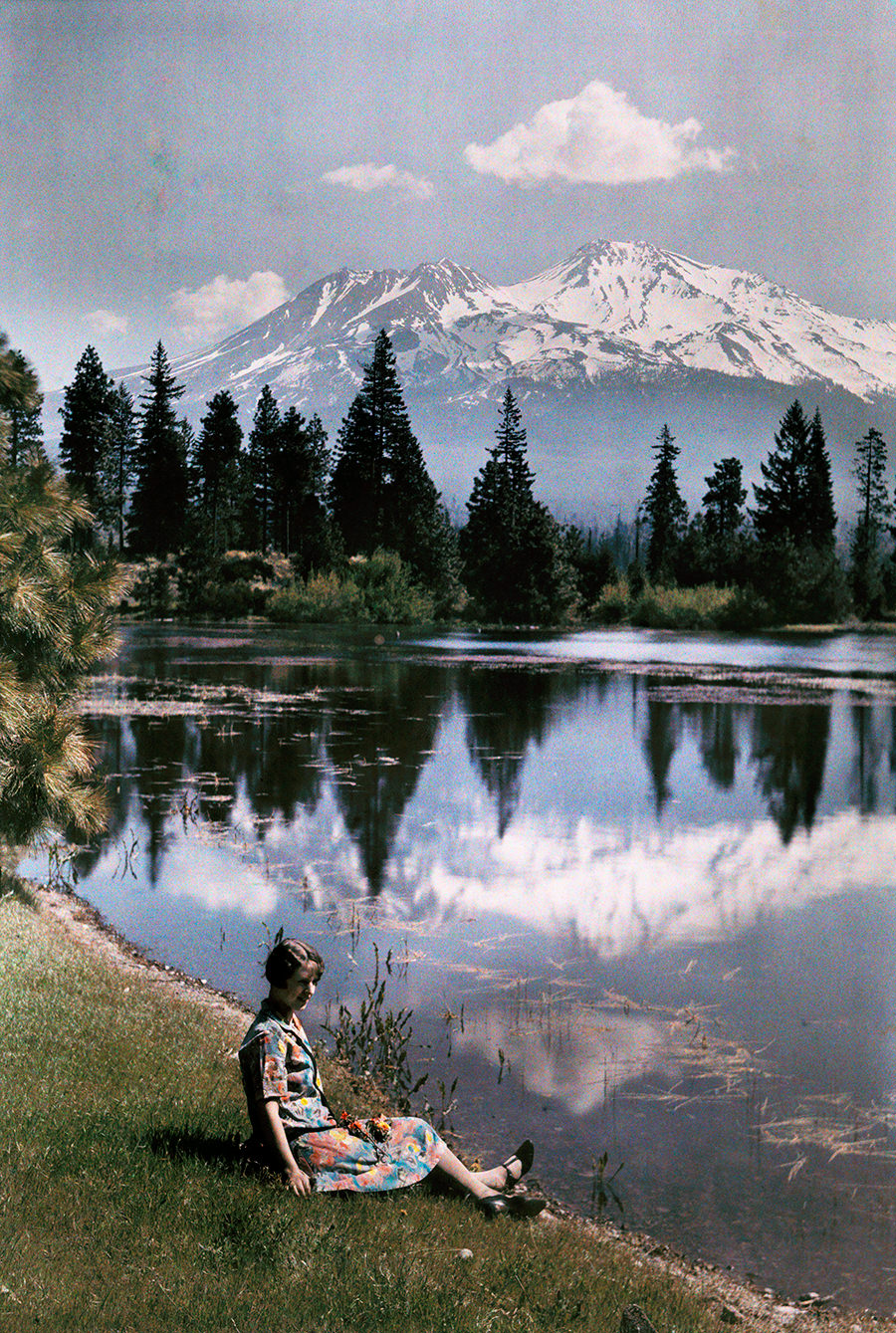 #13 A girl sits by a lake with snow-capped mountains in the background, California, 1929.
