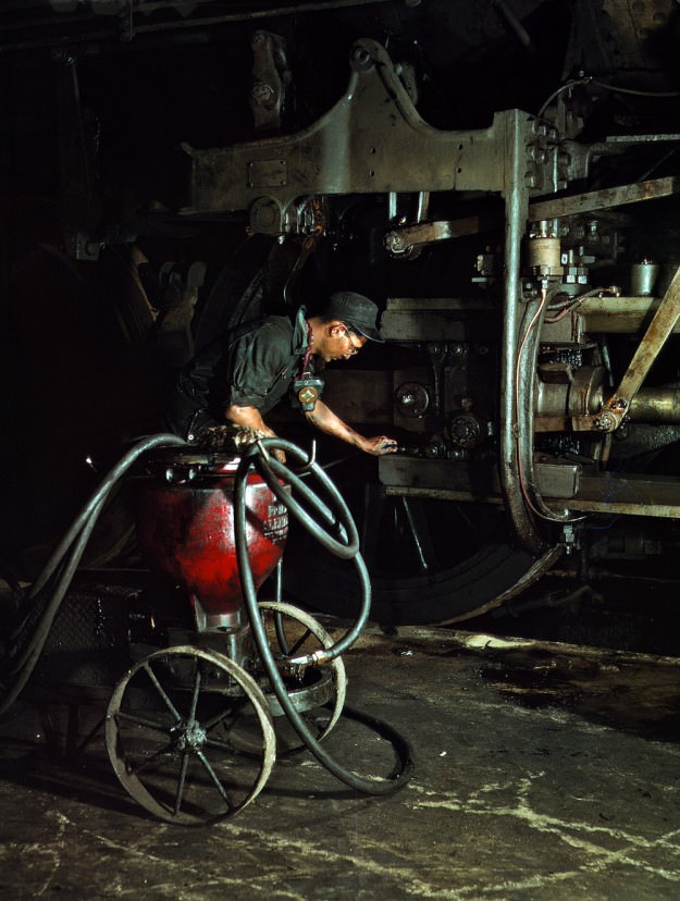 Thomas Madrigal greasing a locomotive in the roundhouse, Rock Island R.R., Blue Island, Ill. April 1943. 4×5 Kodachrome transparency by Jack Delano for the Office of War Information.
