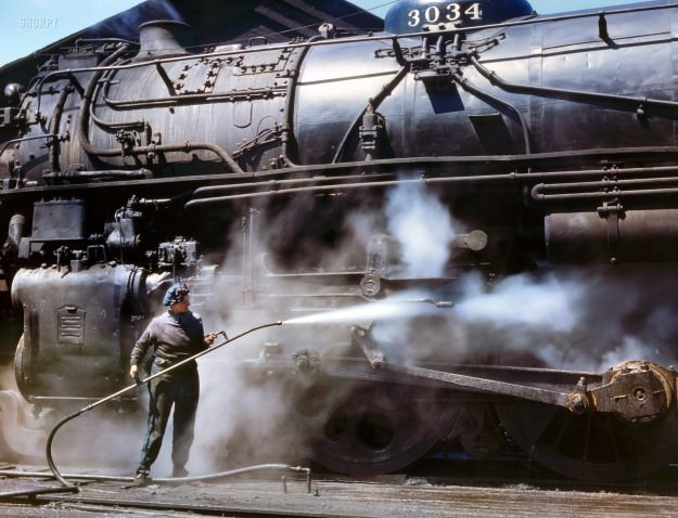 April 1943. “Viola Sievers, one of the wipers at the Chicago &; North Western roundhouse, giving a giant “H” class locomotive a bath of live steam at Clinton, Iowa. Mrs. Sievers is the sole support of her mother and has a son-in-law in the Army.” Kodachrome transparency by Jack Delano.