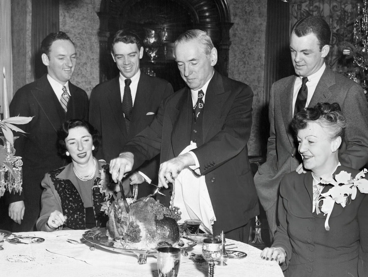 #17 The Curley family surrounds Mayor James Michael Curley as he cuts the Christmas turkey at home in Boston, 1948.