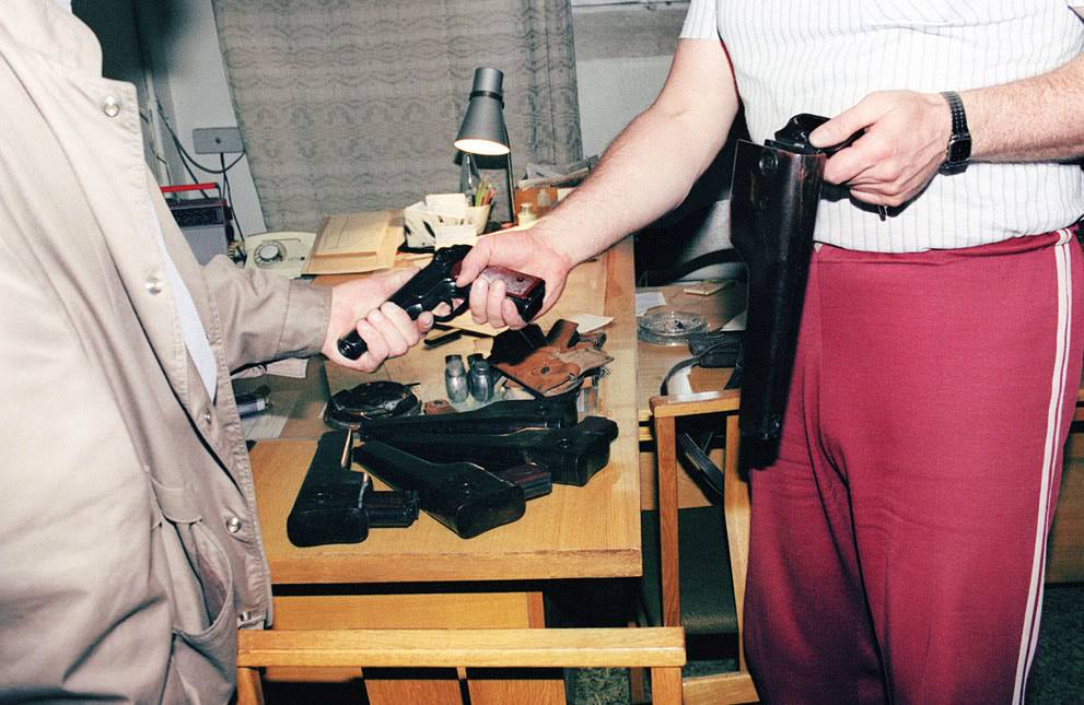 #38 A member of the KGB hands over his weapon to a Lithuanian official in Vilnius, 1991.