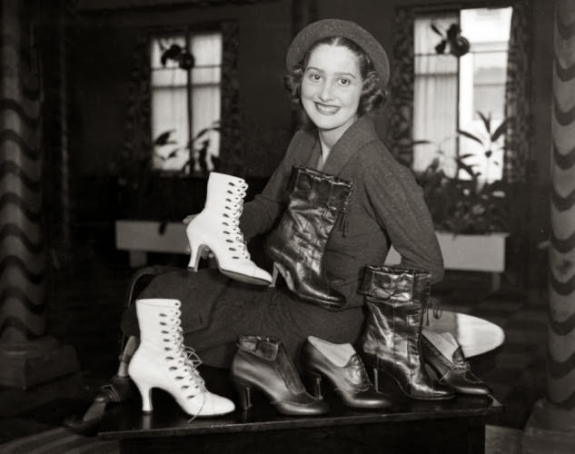 #23 Shoes galore! A model sits behind a stylish display of boots in 1934.