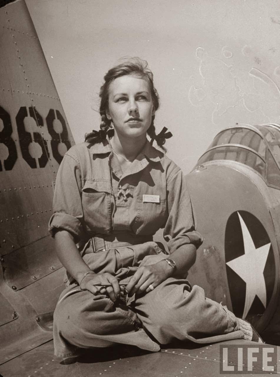 #11 Shirley Slade, pilot trainee in Women’s Fllying Training Detachment, sporting pigtails & GI coveralls as she sits on wing of her Army trainer at Avenger Field.