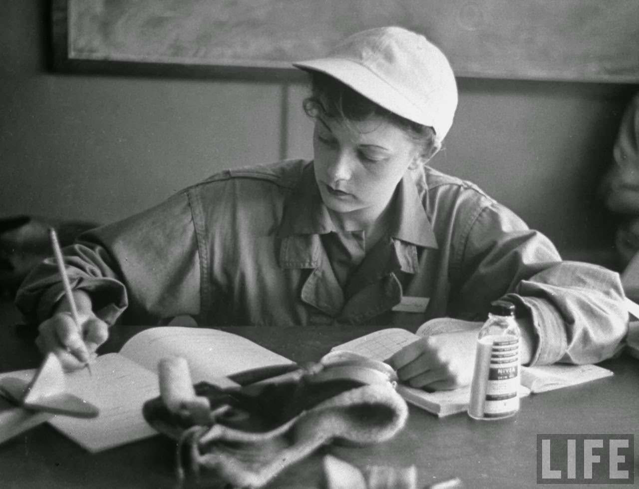 #14 Phyliss Jarman, pilot trainee in the Women’s Flying Training Detachment, wearing her favorite white baseball cap, writing up a report in workbook during training to fly for the Women’s Auxilary Ferrying Squadron, at Avenger Field.