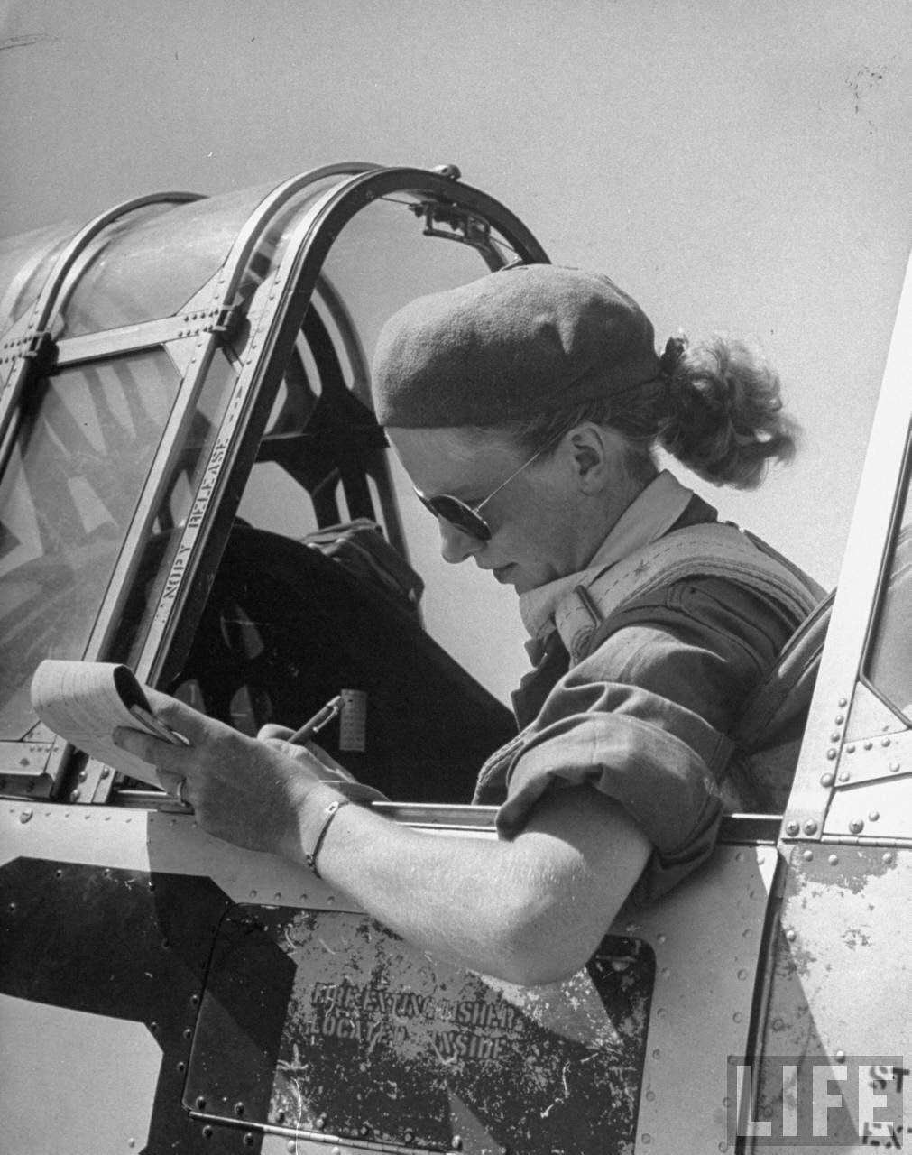 #2 Jean Pearson, pilot trainee in Women’s Flying Training Detachment to later join the all-civilian Women’s Auxiliary Ferrying Squadron, using a beret & a ribbon-tied hair knot to keep hair fr. flying, in cockpit of trainer before takeoff at Avenger Field.