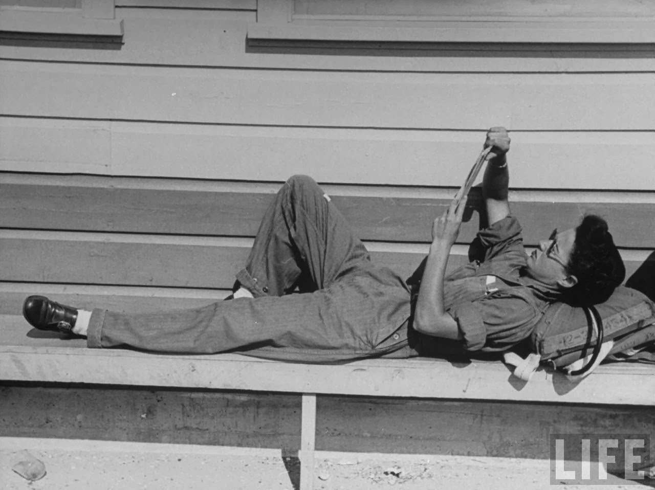 #6 Jean Landis, a member of the Women’s Flying Training Detachment, reading while using her parachute for a pillow as she relaxes between instrument training flights at Avenger Field.