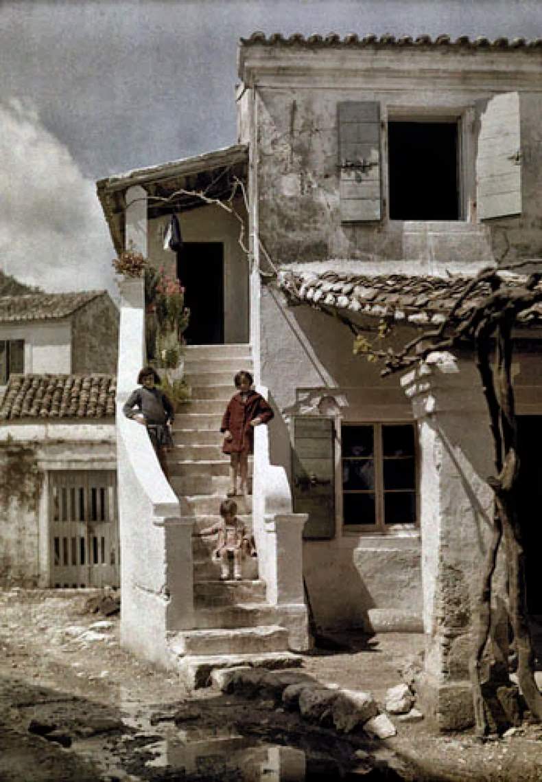 Girls stand on a stairway of a house in a Greek fishing village, Benizze, Corfu.