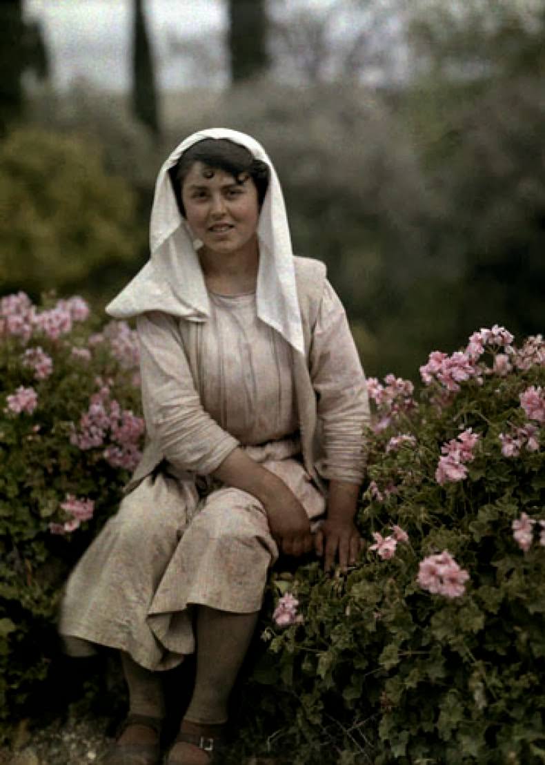 Young woman sitting in a garden of flowers, Corfu.