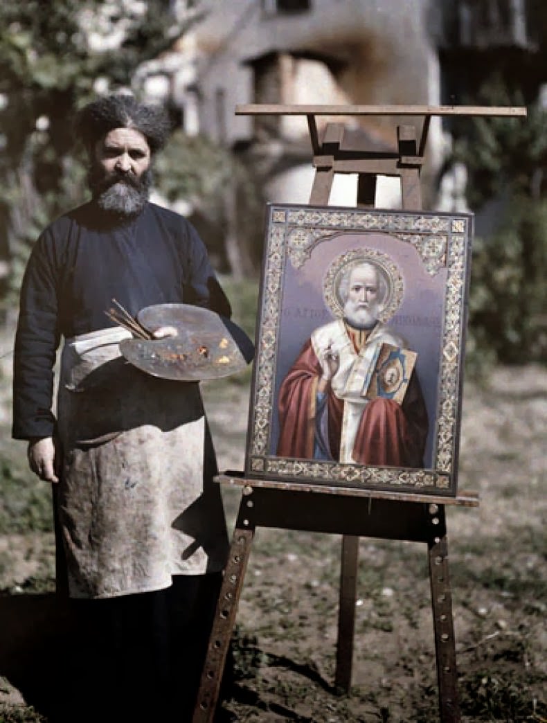 Artist from Mt. Athos stands next to painting of Saint Nicholas.