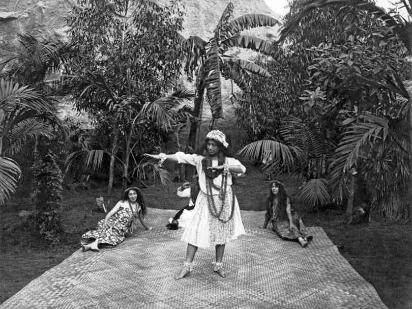 #88 A Hawaiian woman dances on a grass mat while two other women watch, 1900.